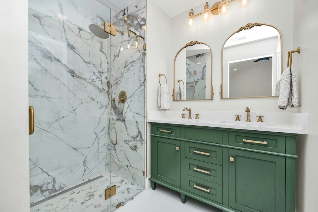 Bathroom with green vanity cabinetry and marble shower