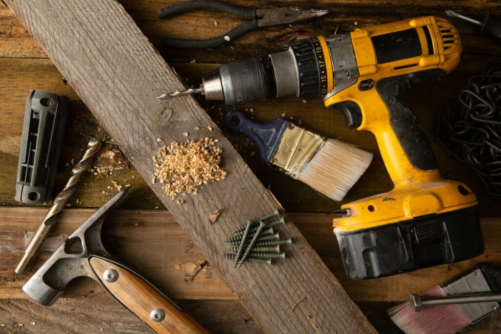 Cordless drill and hand tools arranged on a wooden workbench