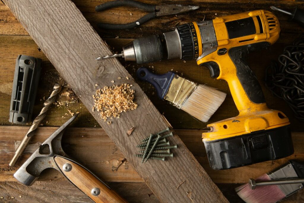 Hand tools and cordless drill on a workbench