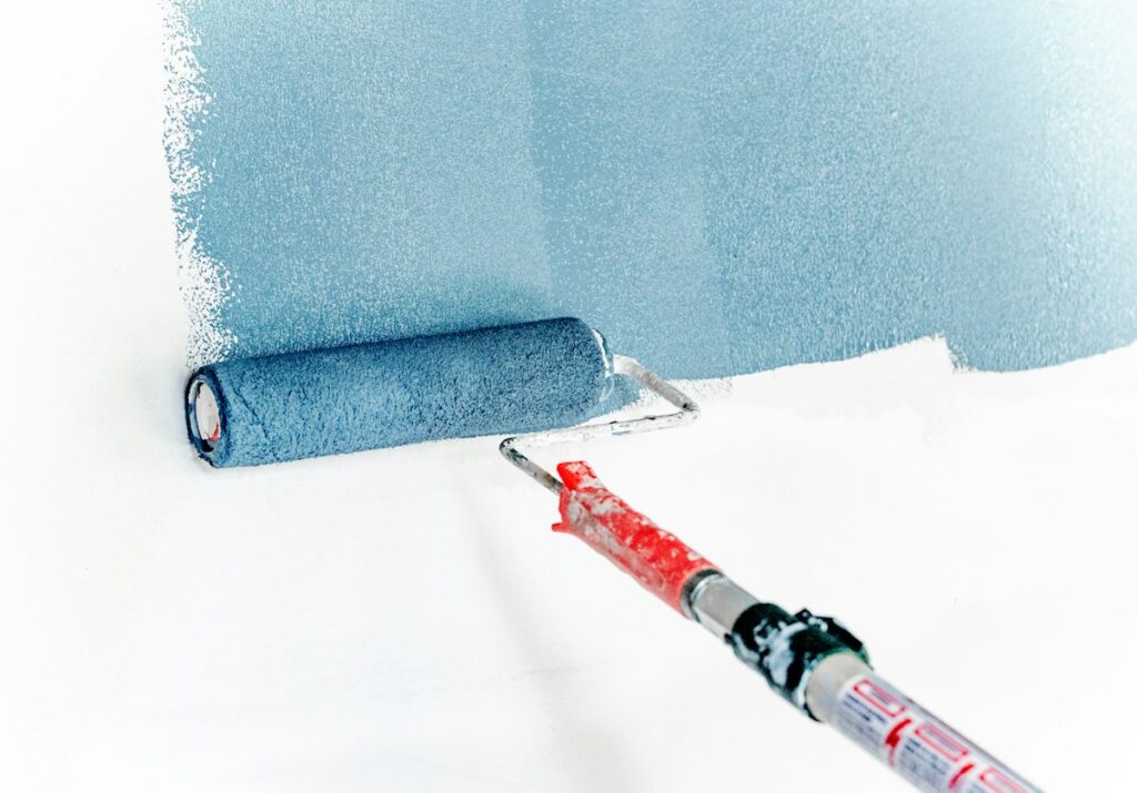 Paint being applied to an interior wall with a long-handled roller