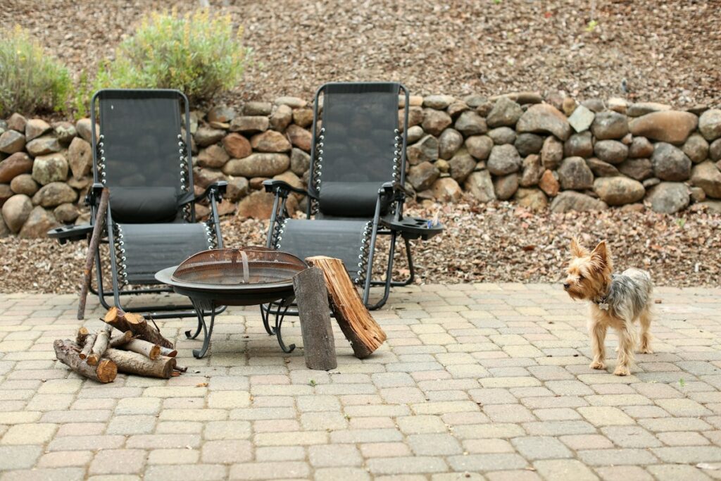 Backyard brick patio with fire pit and chairs